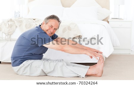 Mature man stretching in his bedroom