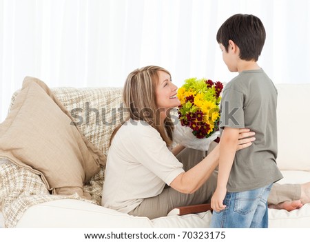 Boy offering flowers to his grandmother at home