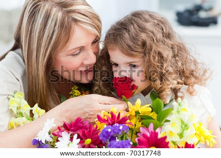 Little girl smelling flowers while her grandmother is smiling