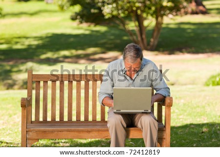 Elderly man working on his laptop in the park