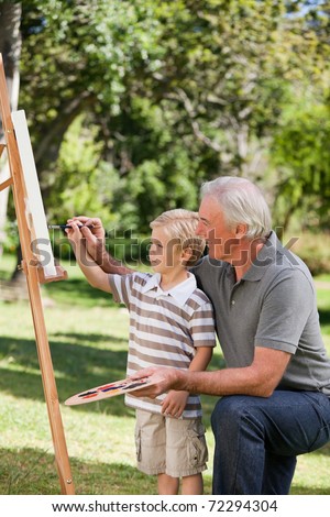 Happy Grandfather and his grandson painting in the garden