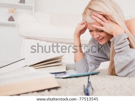 Attractive blond woman lying on a carpet being angry with her computer in the living room