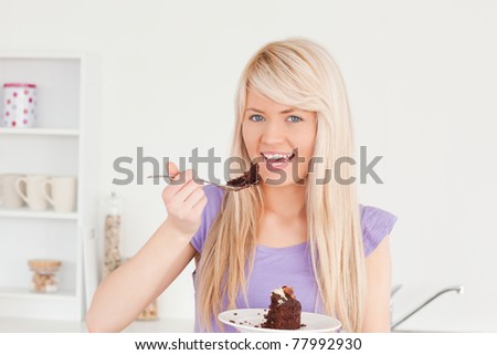 Beautiful caucasian woman eating cake in the kitchen