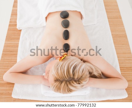Young blonde woman relaxing with hot stones on her back in a Spa center