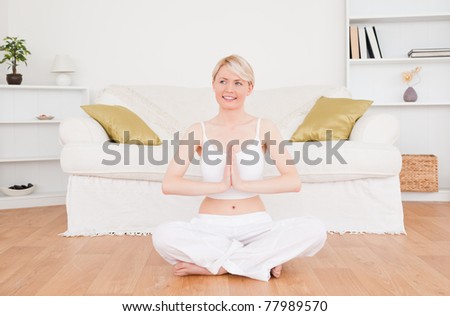 Pretty blonde woman practicing yoga at home
