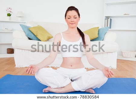 Young female doing yoga on a gym carpet in the living room