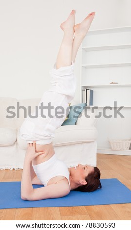 Young attractive red-haired female stretching in the living room in her apartment