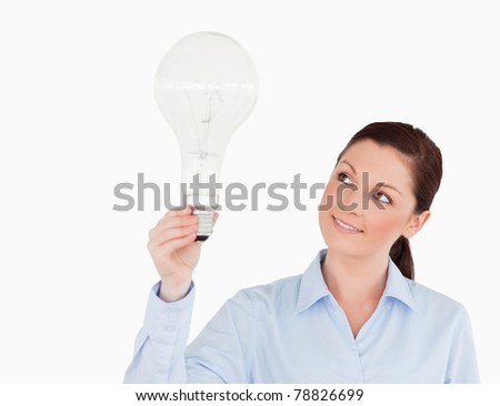 Gorgeous red-haired woman holding a light bulb while standing on a white background