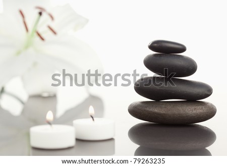 White orchid with lighted white candles and a black pebble stack the camera focus on the object