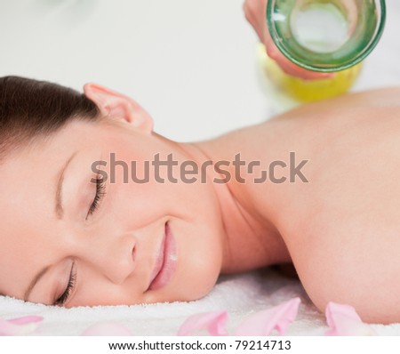 Smiling young woman having massage oil versed on her back in a spa