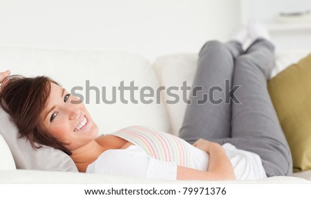 Attractive brunette woman posing while lying on a sofa in the living room