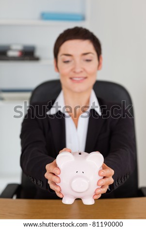 Portrait of an office worker holding a piggy bank in her office
