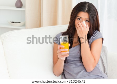 sad woman with orange juice and handkerchief in living room