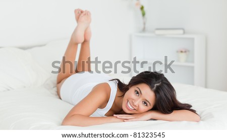 cute woman lying on bed in bedroom with crossed legs