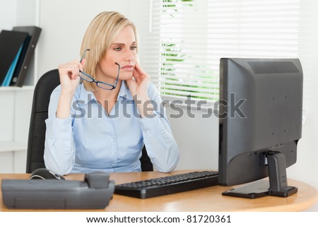 Serious thoughtful woman with glasses looking at screen in an office
