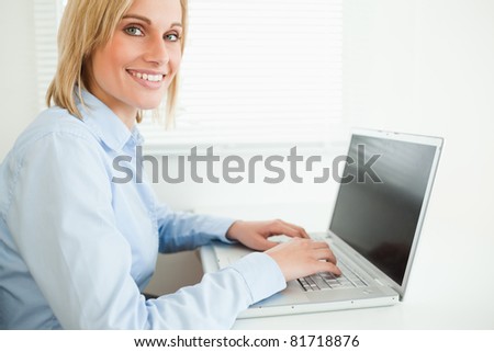 Close up of a gorgeous smiling businesswoman working on laptop looking into camera in her office