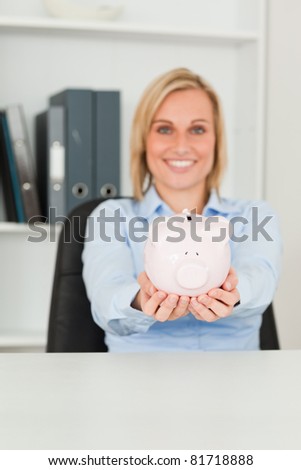 Gorgeous businesswoman holding a piggy bank in her office