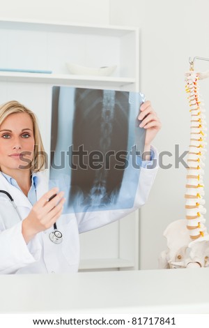 Sad looking doctor holding x-ray looking into camera in her office