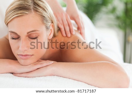 Close up of a smiling woman relaxing with eyes closed on a lounger during a massage in a wellness center