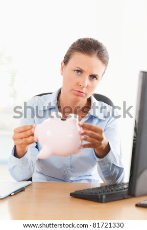 Sad businesswoman with an empty piggy bank looking at the camera