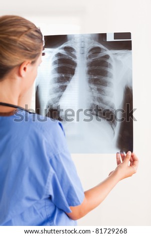 Doctor holding a x-ray having a stethoscope around her neck in the surgery