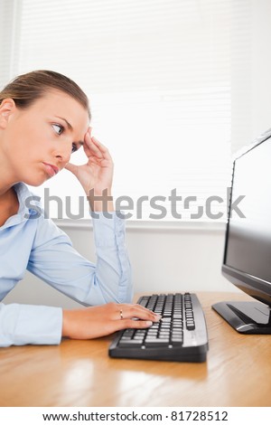 A sad businesswoman is looking into the screen of her pc in an office