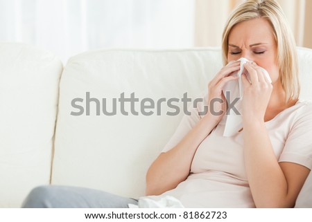Woman blowing her nose in her living room