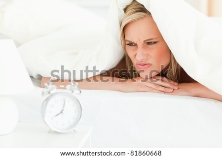Disgruntled blonde woman waking up in her bedroom