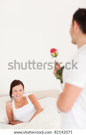 Portrait of man and woman in a bed with a rose in their bedroom