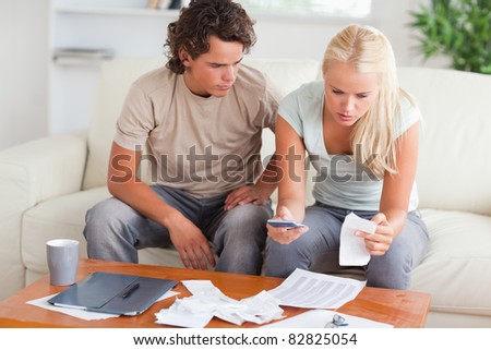 Shocked couple calculating their expenses in the living room