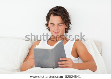 Handsome man reading a book in his bedroom