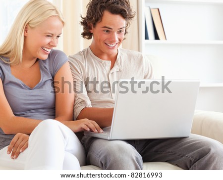 Laughing couple using a notebook in their living room