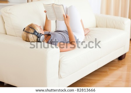 Woman listenning to music while reading a book in her living room