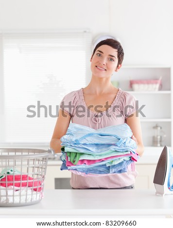 Charming Woman with a pile of clothes in a utility room