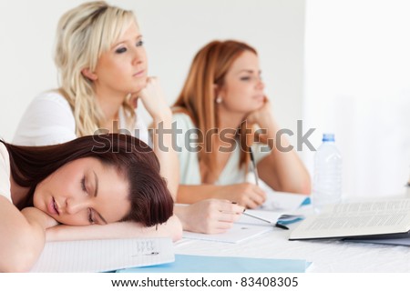 Bored university students one sleeping sitting at a table during class