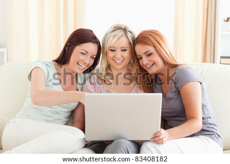 Cheering women lounging on a sofa with a laptop in a living room