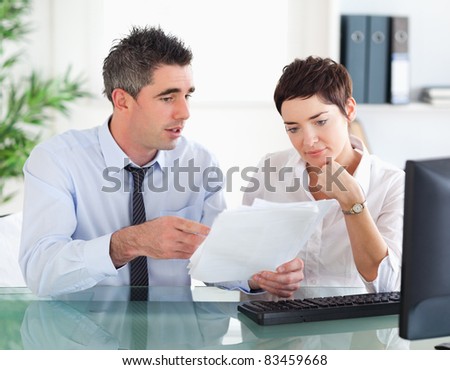 Man pointing at something to his colleague on a document in an office