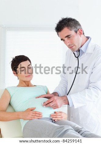 Doctor listening into the belly with a stethoscope in a room