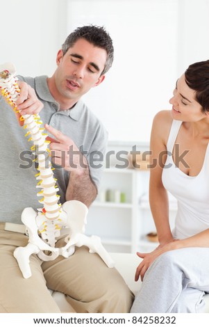 Chiropractor explaining the spine to a woman in a room