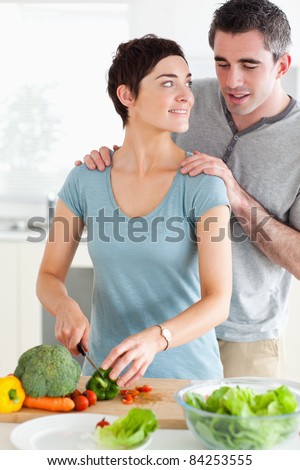 Husband peeking over his wife\'s shoulder in a kitchen