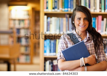 Portrait of a student posing with a book in the library
