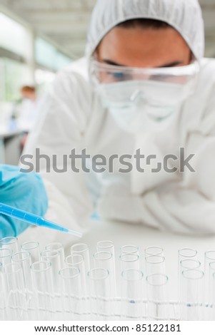 Portrait of a protected female science student dropping blue liquid in a test tube in a laboratory
