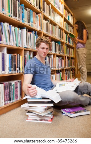 Portrait of a student doing research while his classmate is reading in a library