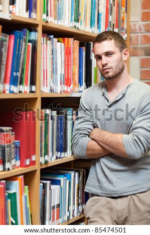 Portrait of a male student leaning on a shelf in a library