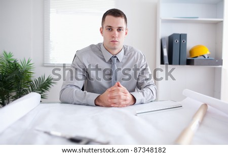Architect sitting behind a table with a construction plan on it