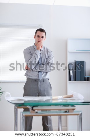 Businessman standing behind table and thinking