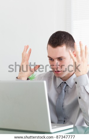 Close up of unhappy young businessman having problems with his laptop