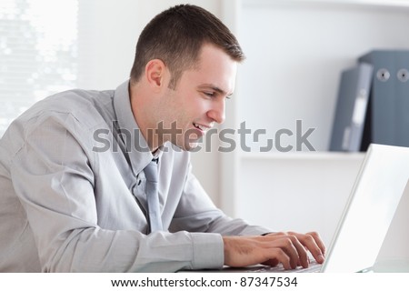 Close up of smiling businessman writing an email with his laptop
