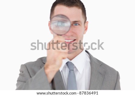 Young businessman looking through a magnifying glass against a white background
