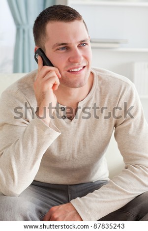 Portrait of a man making a phone call while sitting on a sofa in his living room